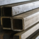 Close-up of stacked steel box section and metal profiles ready for precision fabrication.