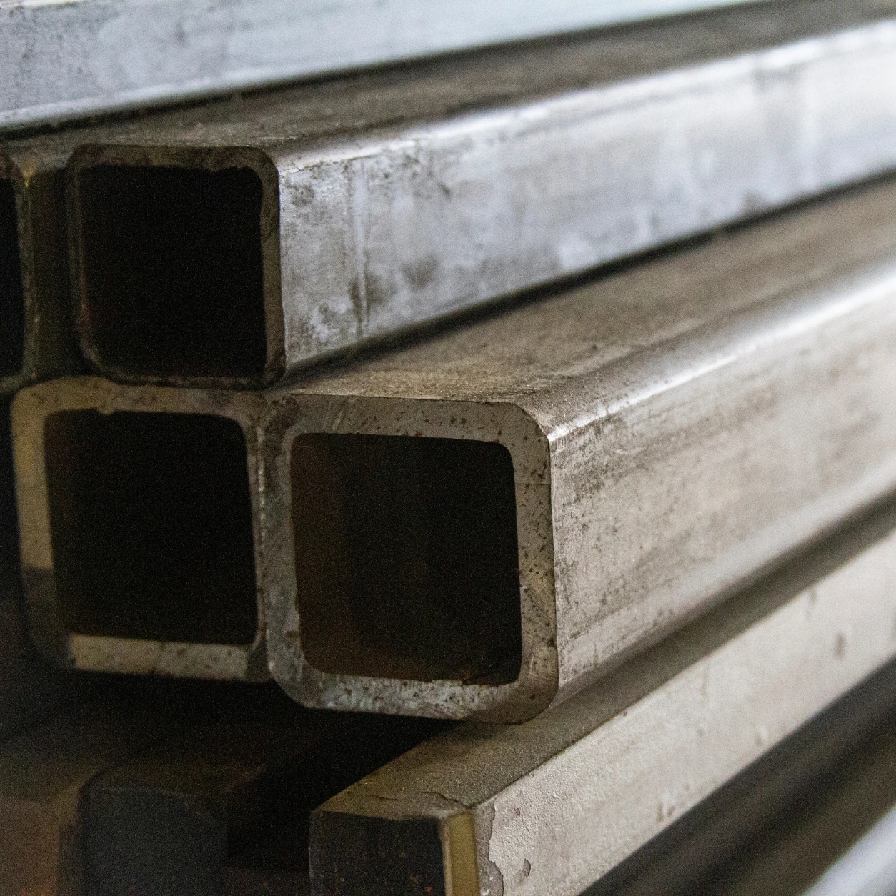 Close-up of stacked steel box section and metal profiles ready for precision fabrication.